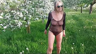 A mature woman is walking around outside in a see-through bodysuit!